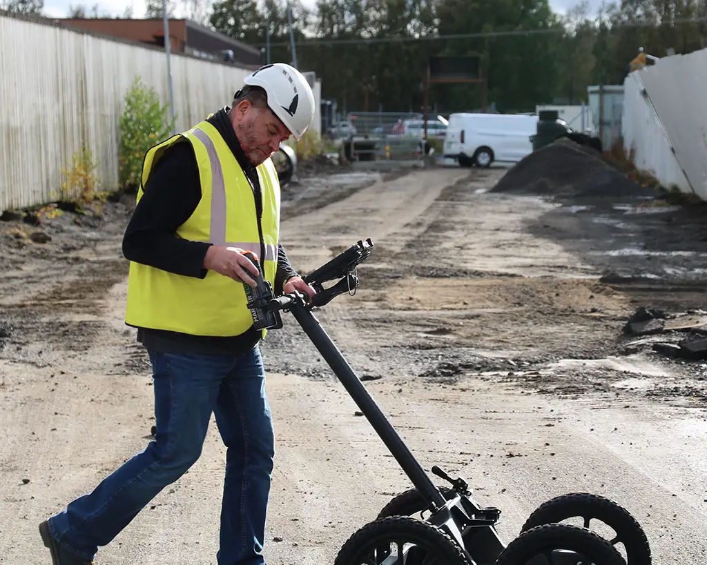 Operator pushing the Easy Locator Lite across rough, uneven ground
